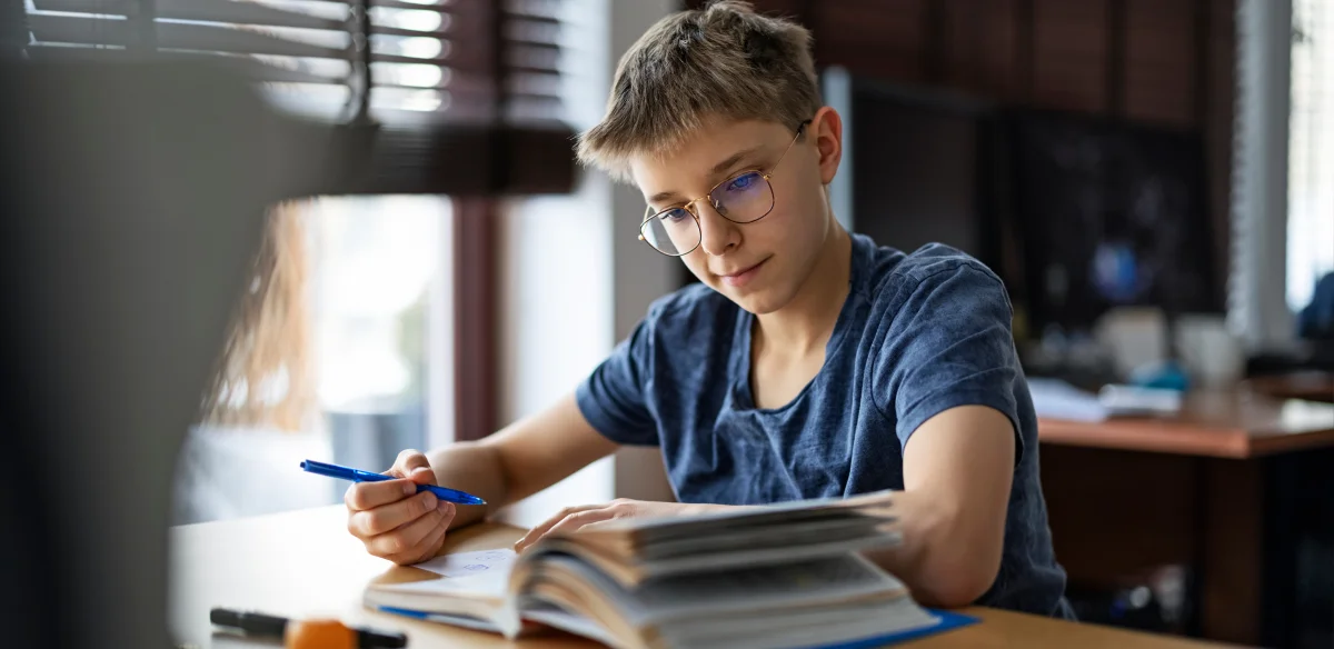 Estudiante de secundaria con gafas y tomando notas